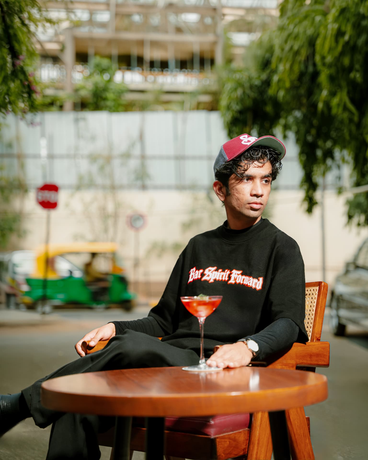 Bar Spirit Forward tee and SF cap seated outside with a cocktail